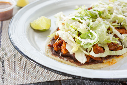 A closeup view of a plate of huarache, in a restaurant or kitchen setting.