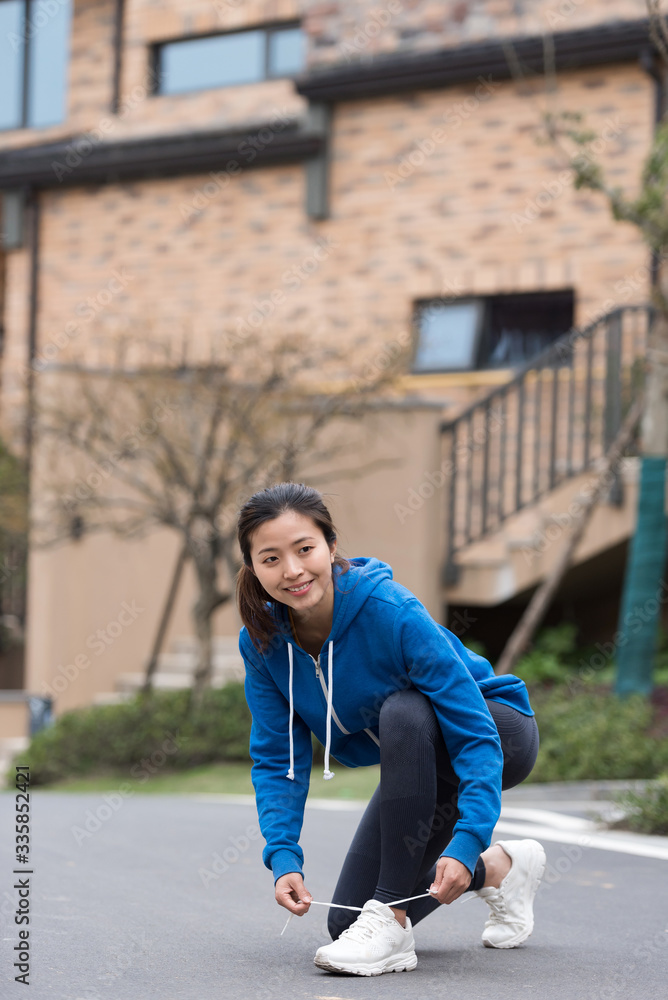 A young Asian woman is squatting and tying shoelaces A young Asian woman is squatting and tying shoelaces