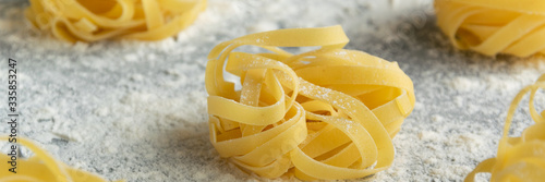 фотографія Handmade italian pasta - tagliatelle on grey floury background