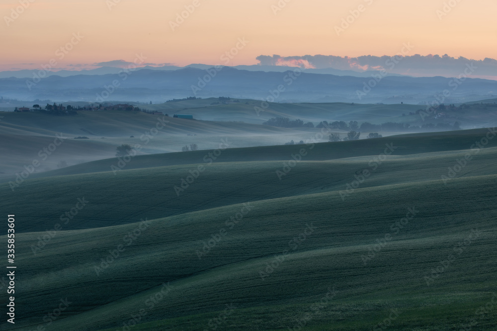 Sunrise glow over a rolling rural landscape. Siena, Italy.