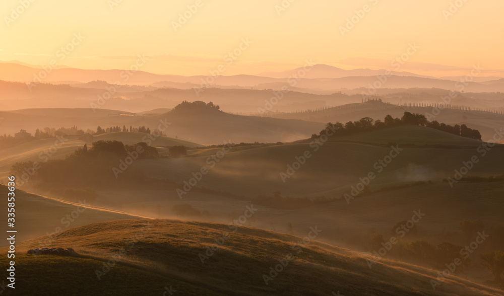 Sunrise glow over a rolling rural landscape. Siena, Italy.