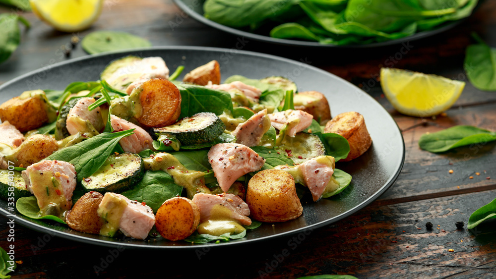 Salmon, new potato, courgette and spinach salad on wooden table