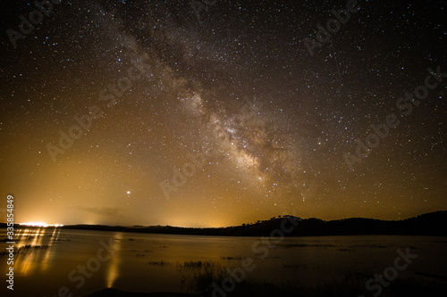 Night sky with stars and Milky Way over mountain lake
