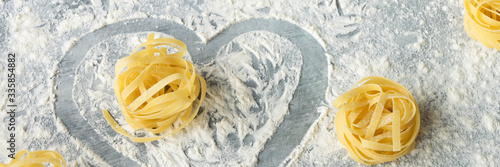 фотографія Handmade italian pasta - tagliatelle on grey floury background