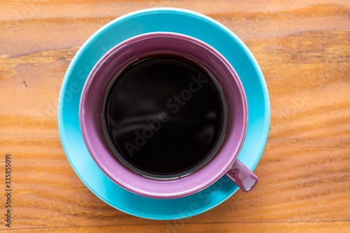 Taza de colores con café sobre mesa de madera