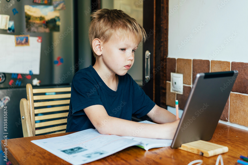 A schoolboy does homework using internet communication and technical gadgets. Home-based family education. Learning from home online. A schoolboy does homework using internet communication and technical gadgets. Home-based family education. Learning from home online.