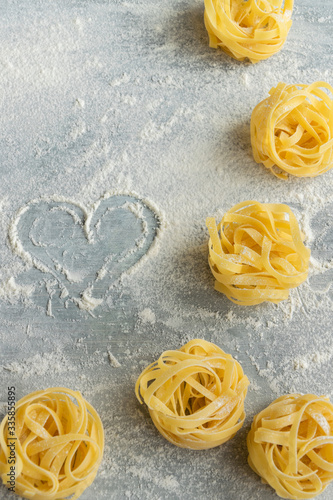 Handmade italian pasta - tagliatelle on grey floury background
 photo