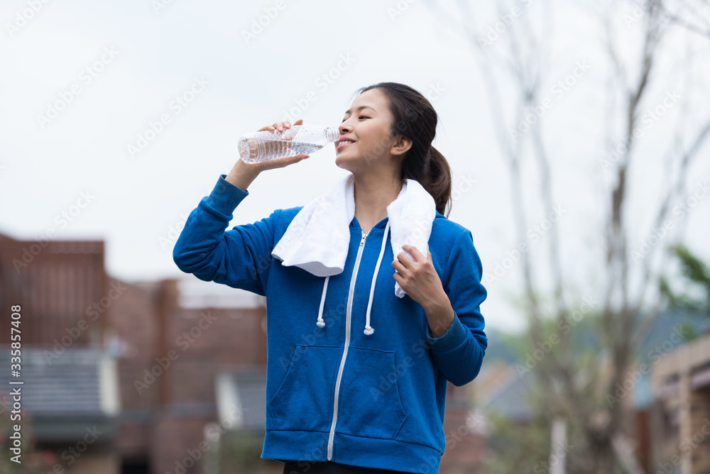 A young Asian woman is resting and drinking water A young Asian woman is resting and drinking water