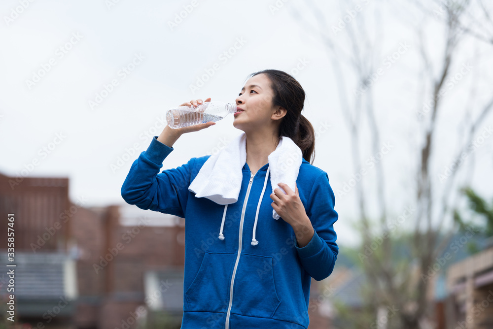 A young Asian woman is resting and drinking water A young Asian woman is resting and drinking water