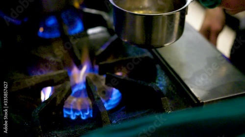 Chef taking a pot off a gas burner in a commercial kitchen. photo