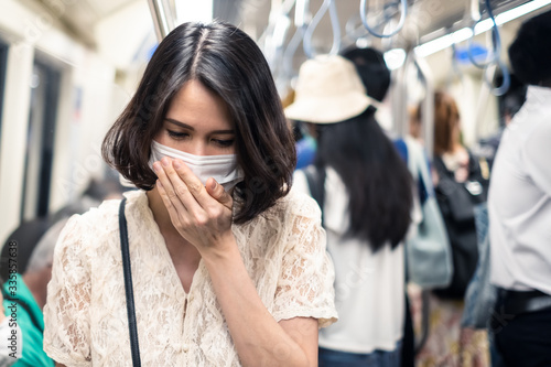 Asian woman wearing mask for prevent dusk pm 2.5 bad air pollution and coronavirus or covid-19 have a cough, fever. Girl wears mask due to bad smell and prevent virus infection from people in subway.