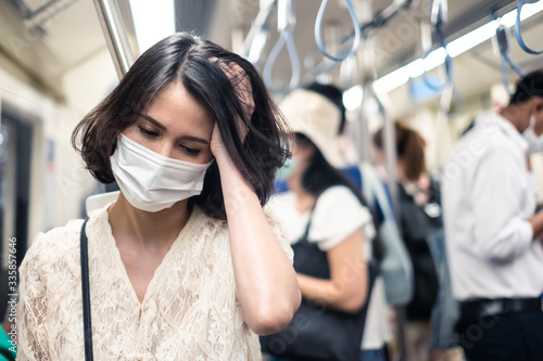 Asian woman wearing mask for prevent dusk pm 2.5 bad air pollution and coronavirus or covid-19 have headache, fever. Girl wears mask due to bad smell and prevent virus infection from people in subway.