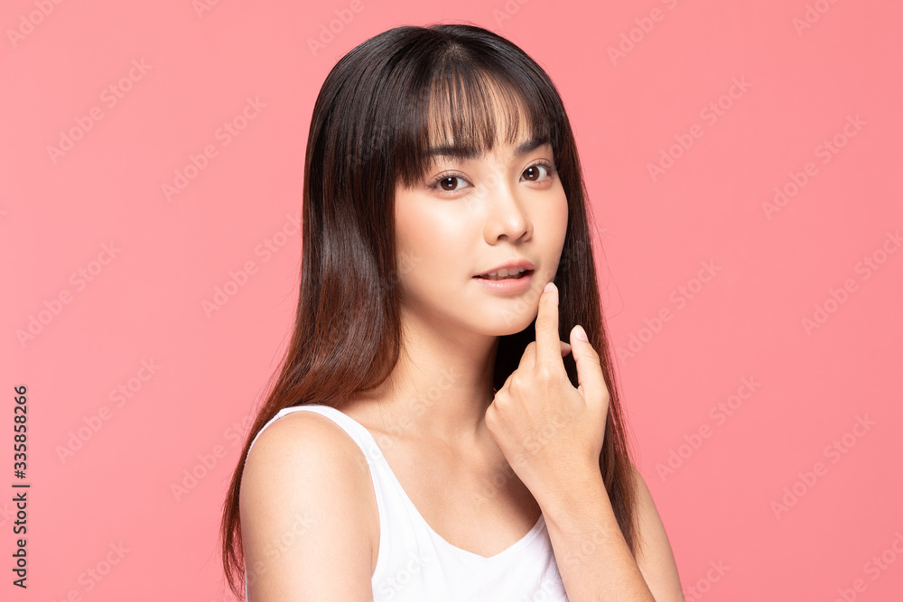 Fototapeta premium Young Beautiful Asian woman smile touching soft cheek with clean and fresh skin Happiness and cheerful with positive emotional,isolated on pink background,Beauty Cosmetics and spa Treatment Concept