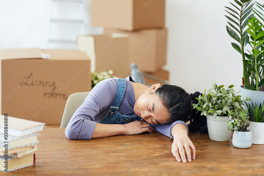 Portrait of exhausted Asian woman sleeping on wooden table while packing for moving or relocation to new house, copy space Portrait of exhausted Asian woman sleeping on wooden table while packing for moving or relocation to new house, copy space