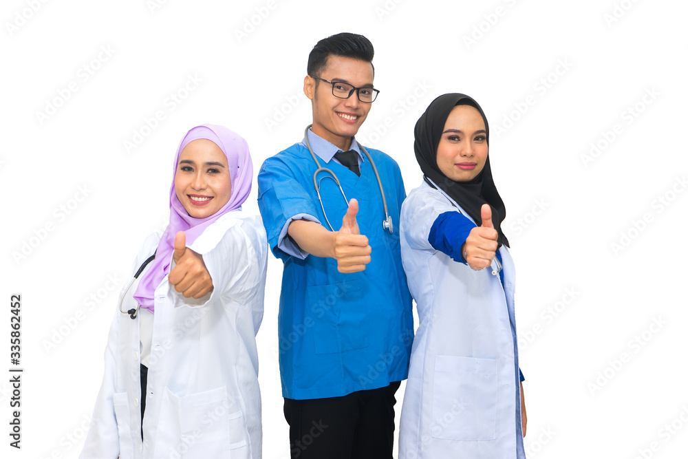Successful team of asian muslim medical doctors showing thumbs up sign and smiling while standing on white background. Successful team of asian muslim medical doctors showing thumbs up sign and smiling while standing on white background.