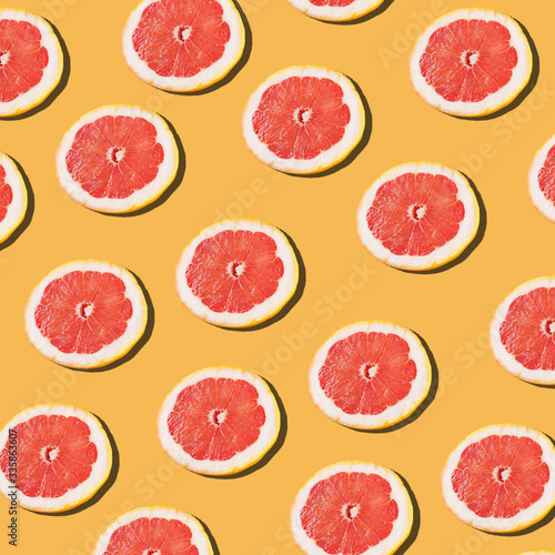 Pink ripe grapefruit slices on the orange background pattern.