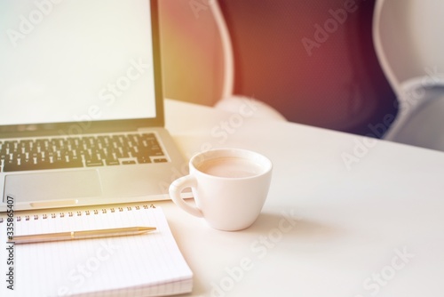 Laptop mockup on work desk in sunset. Close-up laptop  coffee  with morning light. Modern  thin laptop design.White. Isolated screen for mockup. Laptop profile. Home office