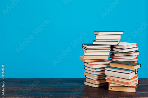 many stacks of educational books for learning preparation for college exams on a blue background photo