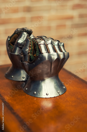 Medieval armor, detail of an ancient armor. Steel gloves on wooden background.