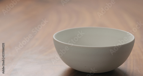 empty whiute bowl on walnut table with copy space photo