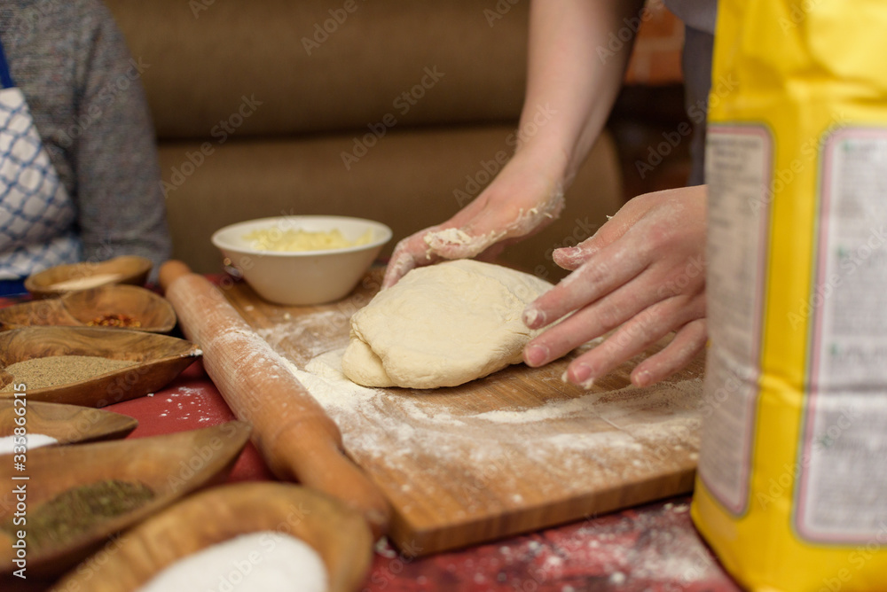 Female hands knead the dough.