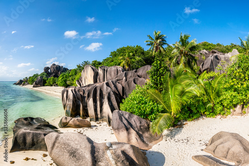 Tropical beach with palm trees and rocks on the island of La Digue, Seychelles, Africa