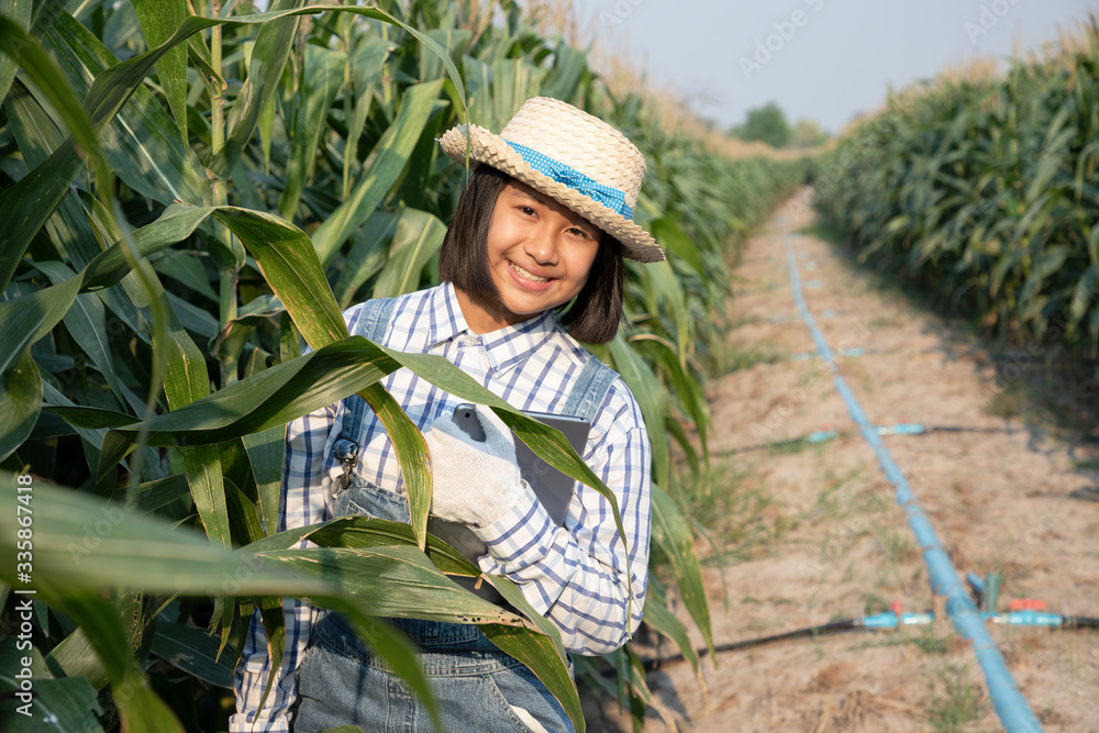 Young little girl relaxing and see product tracking with tablet in corn field. She’s fresh smile and surprise in the evening. Corn products are used to produce food for humans and animals.