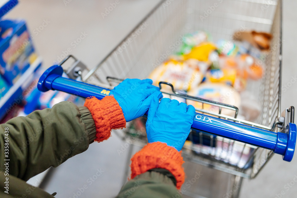 girl in medical gloves in a supermarket with a trolley girl in medical gloves in a supermarket with a trolley