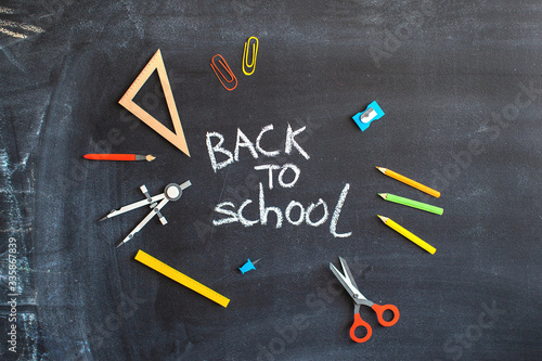 Back to school on black chalk board background. Tools for education. Banner with handmade lettering. 