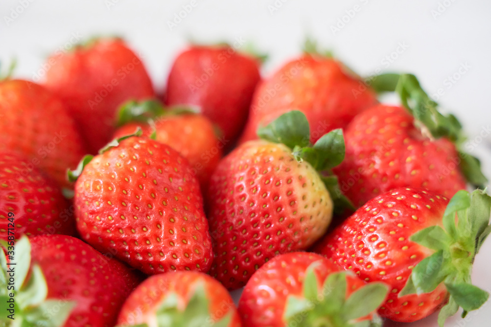 Fresh strawberries on a white plate on a soft wooden base Fresh strawberries on a white plate on a soft wooden base