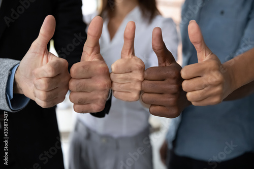 Close up view of diverse business team people hands showing thumbs up like finger gesture recommendation or good job choice. Professional multicultural team recommend corporate service. photo
