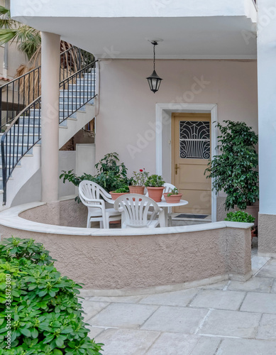 house entrance with small terrace, table and chairs, door and stairway to the next floor, Athens Greece