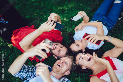 Excited friends using smartphones on grass