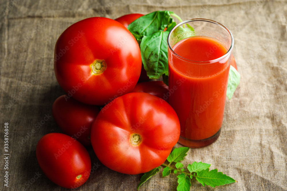 Glass of fresh tomato juice and tomatoes around on cloth background Glass of fresh tomato juice and tomatoes around on cloth background