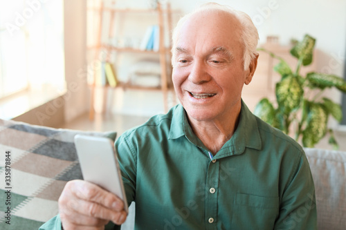 Elderly man with mobile phone at home