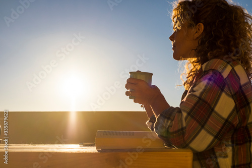 Hipster caucasian young woman outdoor enjoy tea or coffee cup looking at hhe sun - sunlight and warm tones image with people photo