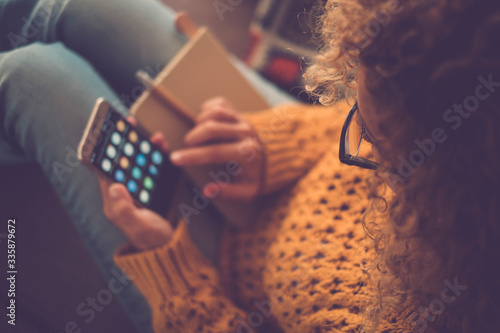 Closeup of woman viewed from above using a smart phone at home for work or social media sharing life activity - focus on eyeglasses and defocused background - yellow colors photo