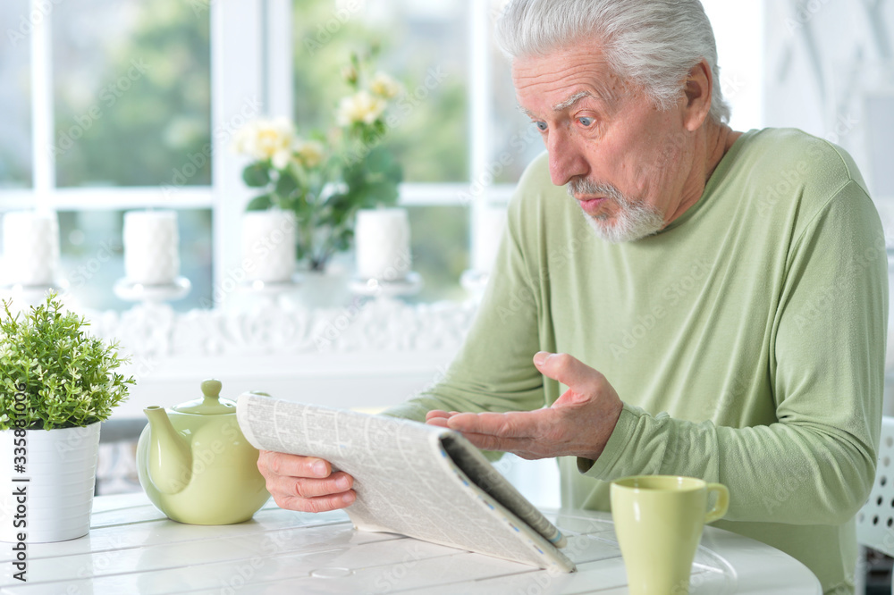 Portrait of emotional senior man reading newspaper Portrait of emotional senior man reading newspaper