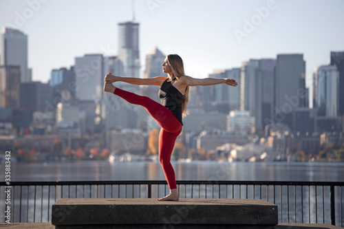 Beautiful Woman Standing Yoga Pose Revolving Extended Hand to Foot in Front of City Skyline