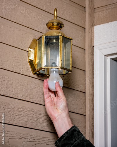 фотографія Homeowner replaces a light bulb in an outdoor light fixture