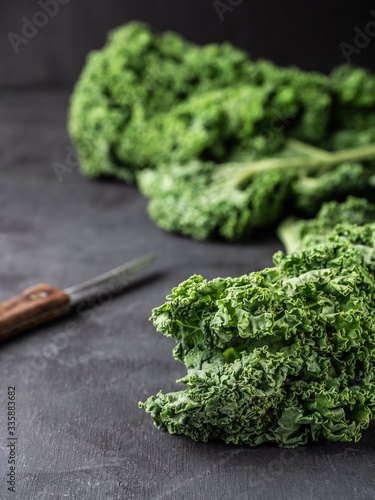 Fresh green kale leaves and knife on dark table. photo