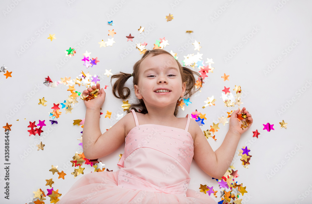 Cute girl in dress lies in confetti
