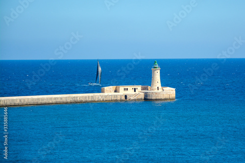 Maritime landscape view lighthouse by the entry of harbor in a sunny day