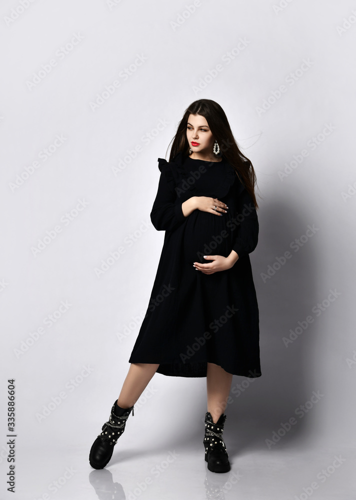 Young beautiful slim pregnant woman with long hair in black long dress. Pregnancy fashion look concept