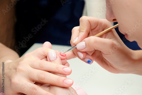 The manicure master applies a shiny nail Polish to the client s nails in a beauty salon. drawing a heart on the client s nails. Close up.