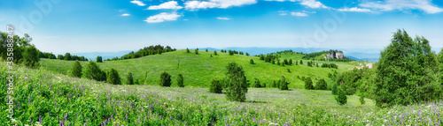 Green meadow and blue sky with clouds. Beautiful summer landscape in the hilly mountains. Natural Park Bolshoi Thach. Adygea, Russia