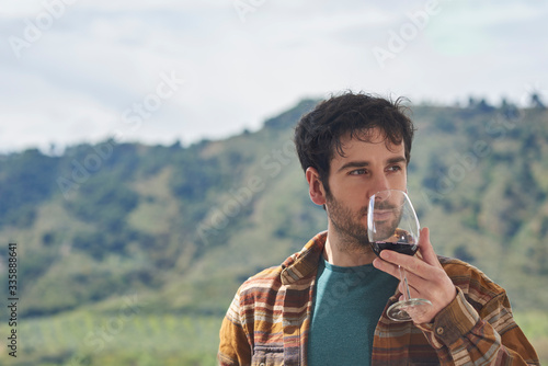 
Man tastes a glass of red wine on a terrace with a view. The image has space for a text. photo