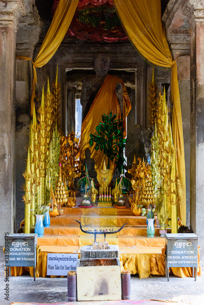 Statue of the Buddha wearing a saffron robe at an altar inside the UNESCO World Heritage Site of Angkor Wat, Siem Reap, Cambodia