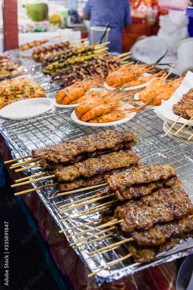 Skewers of barbequed pork and chicken with prawns at a street food restaurant, Bangkok, Thailand