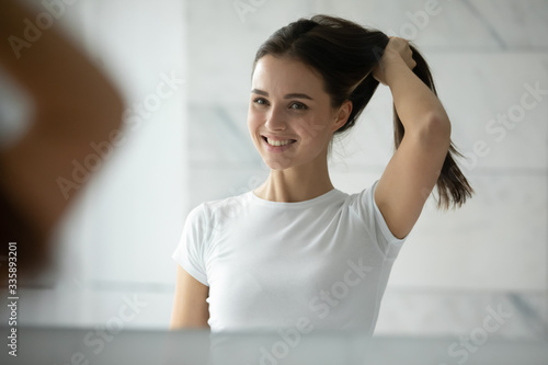 фотографія Beautiful girl look in mirror in bathroom touch healthy thick hair after saloon